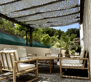 Réservation en ligne de l'appartement : Vue inverse de la terrasse extérieure de l'appartement, mettant en avant sa table basse ainsi que ses canapés et fauteuils.