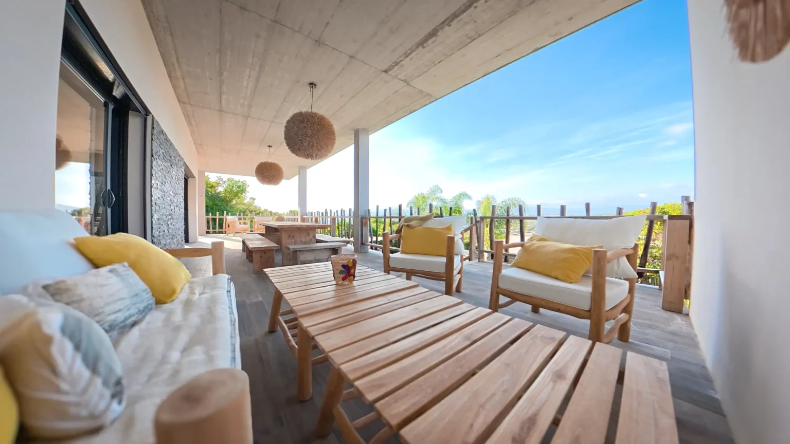 Grande terrasse couverte avec mobilier en bois, fauteuils et vue dégagée à la villa Casa Di Simone à Pietrosella en Corse du Sud.