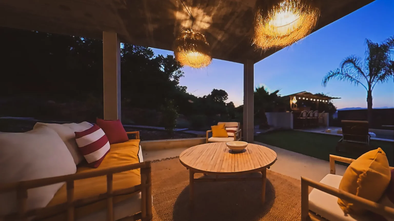 Salon de terrasse ombragé avec mobilier en bambou et luminaires en osier à la Casa Di Simone à Pietrosella.